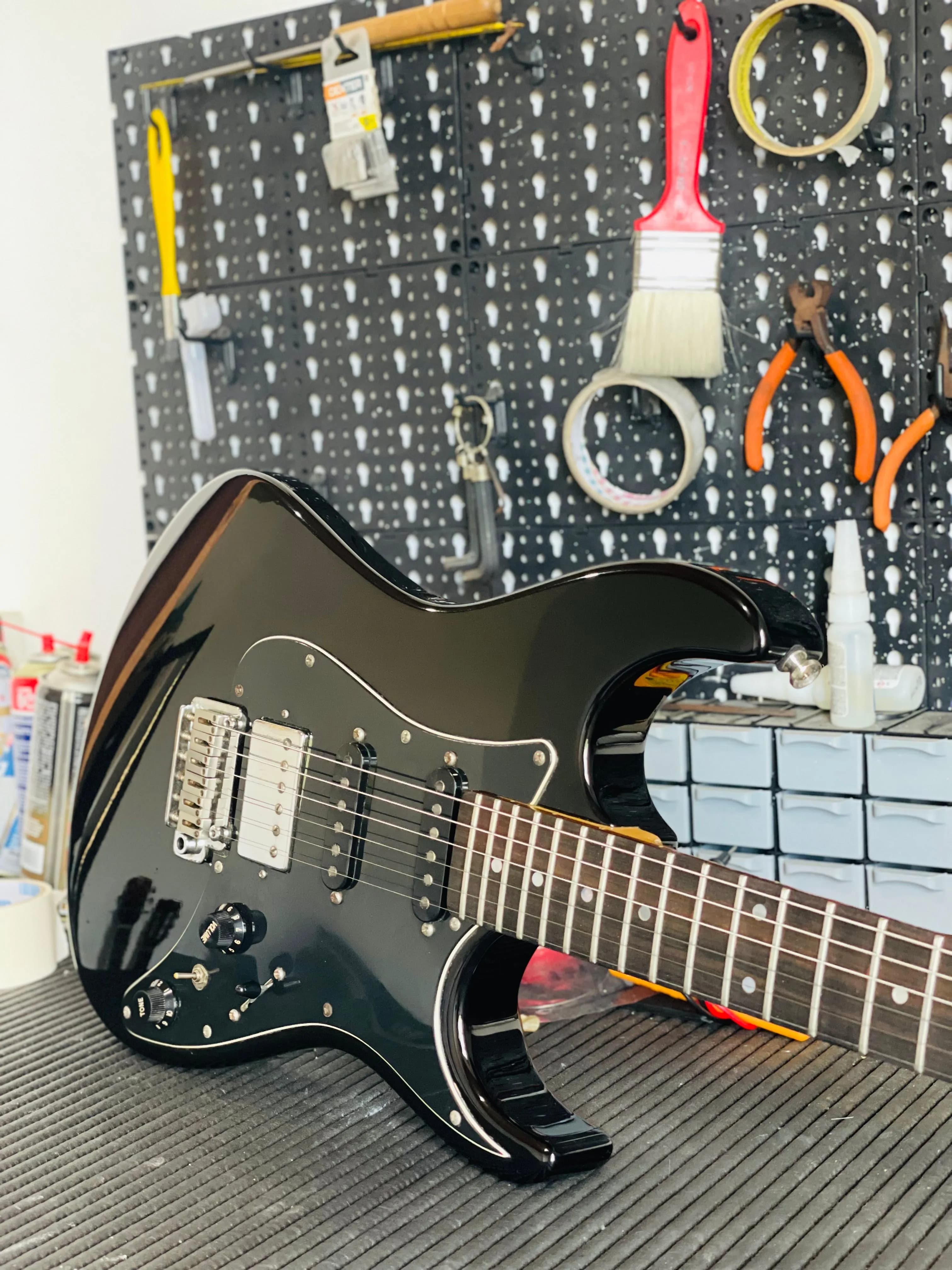 Guitarra Stratocaster preta na bancada do luthier