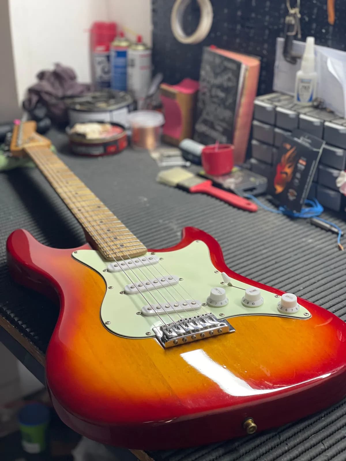 Guitarra stratocaster cherry sunburst com escudo mint finalizada na bancada da oficina