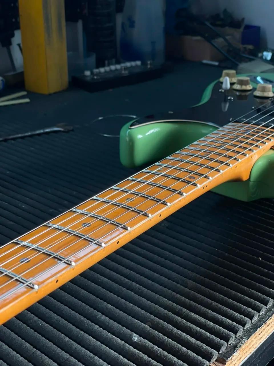Escala de maple com trastes polidos de guitarra verde em perspectiva na bancada